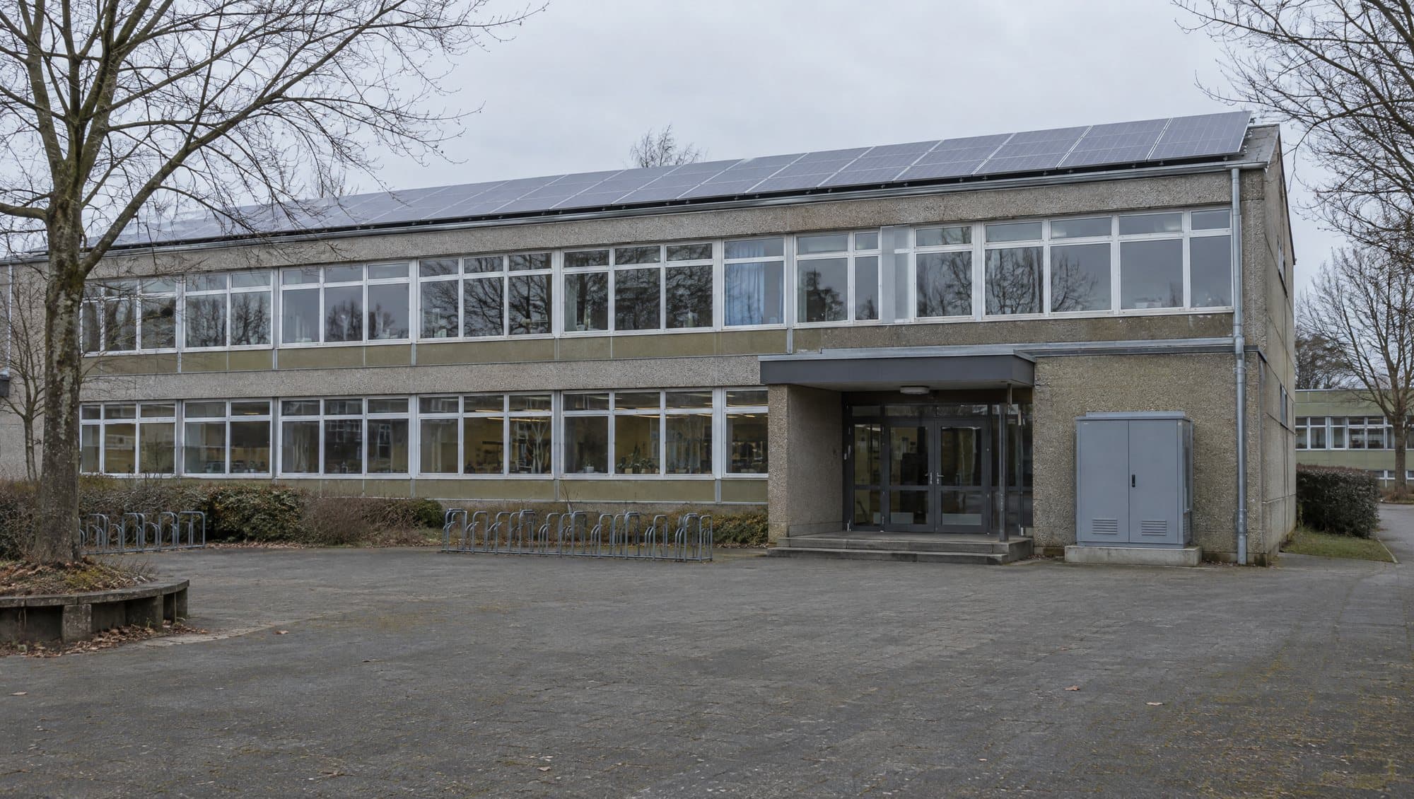Schulgebäude mit Photovoltaik auf dem Flachdach und Speicherschrank